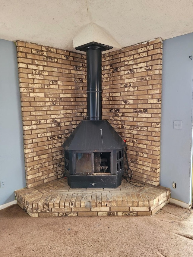 interior details featuring carpet flooring, a textured ceiling, and a wood stove