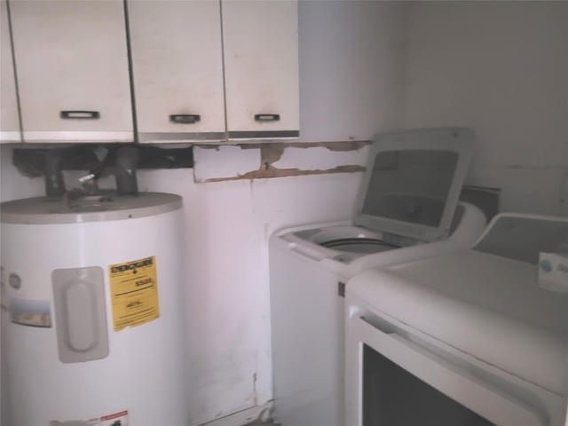 clothes washing area with cabinets, independent washer and dryer, and water heater