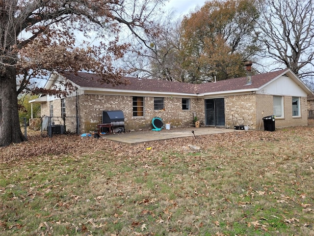 rear view of property featuring a yard, central AC unit, and a patio area