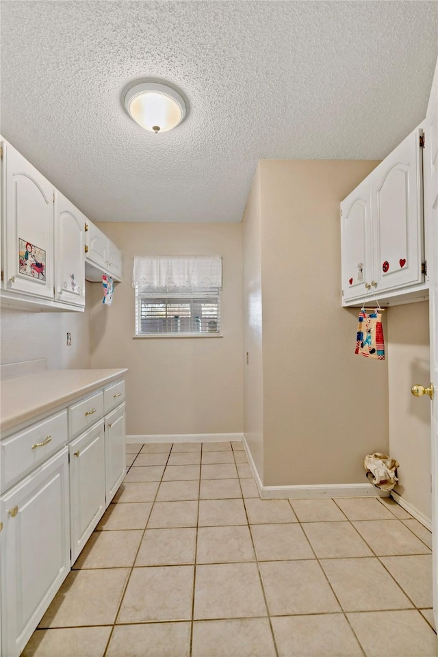 washroom with a textured ceiling and light tile patterned floors