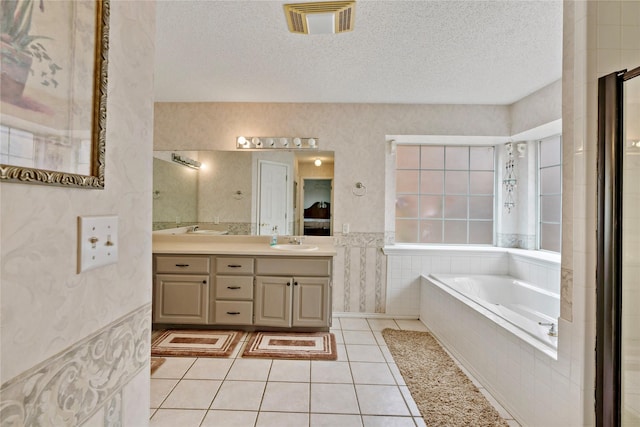 bathroom featuring vanity, tiled bath, tile patterned floors, and a textured ceiling