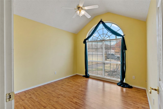 empty room with vaulted ceiling, a textured ceiling, ceiling fan, and light wood-type flooring