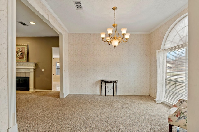 unfurnished room featuring a fireplace, carpet floors, ornamental molding, a textured ceiling, and an inviting chandelier