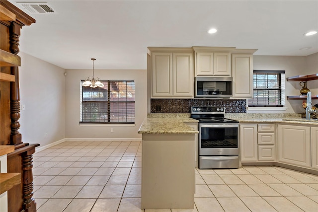 kitchen featuring light tile patterned floors, stainless steel appliances, light stone countertops, cream cabinets, and decorative backsplash