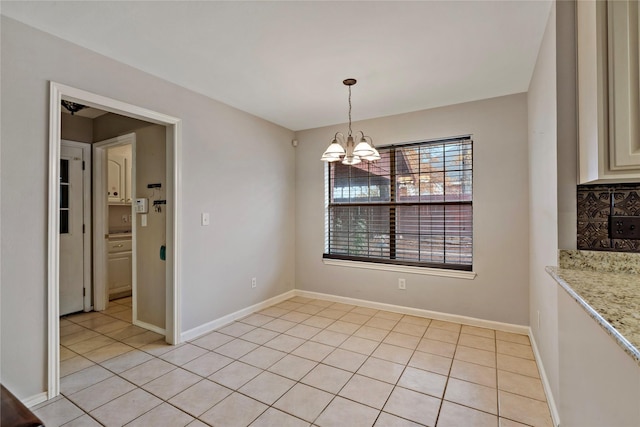 unfurnished dining area featuring light tile patterned flooring and a chandelier