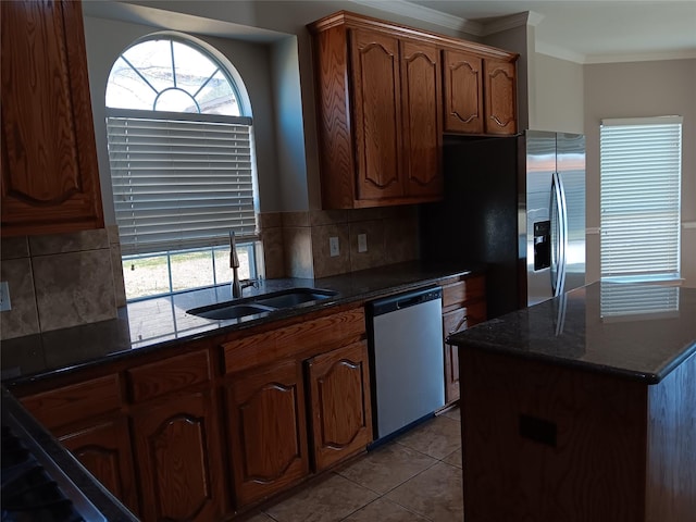 kitchen featuring appliances with stainless steel finishes, sink, decorative backsplash, light tile patterned floors, and crown molding