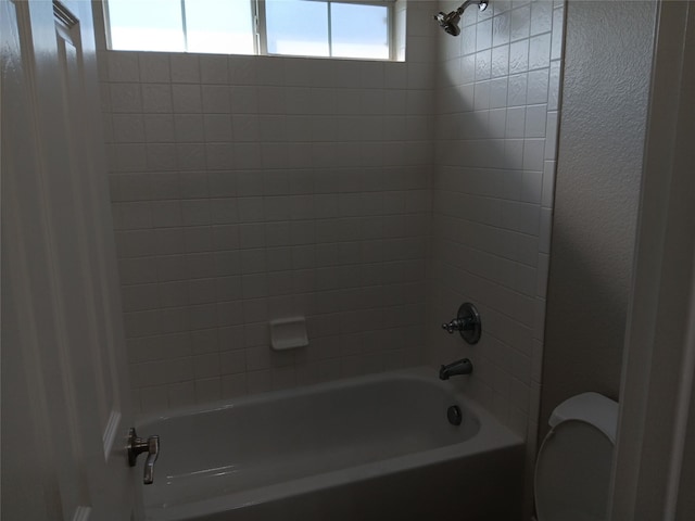 bathroom with tiled shower / bath and toilet