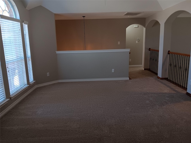 carpeted spare room with a healthy amount of sunlight and vaulted ceiling