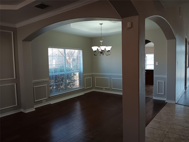 empty room with a chandelier, hardwood / wood-style flooring, and crown molding