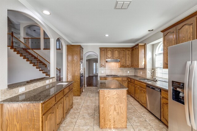 unfurnished living room featuring arched walkways, lofted ceiling, a ceiling fan, wood finished floors, and stairs