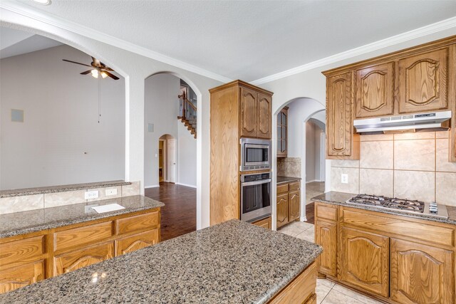 unfurnished living room featuring wood finished floors, a ceiling fan, a towering ceiling, and arched walkways
