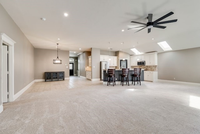 unfurnished living room with ceiling fan, light colored carpet, and vaulted ceiling