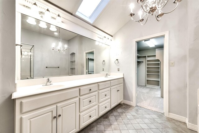 bathroom with lofted ceiling with skylight, vanity, and a notable chandelier