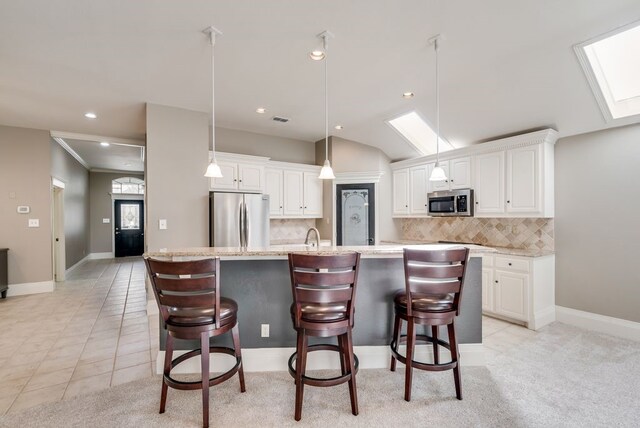 kitchen with an island with sink, white cabinets, and stainless steel appliances