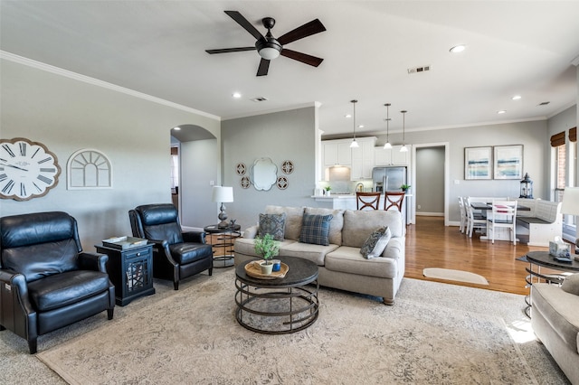 living room with light wood-type flooring, ceiling fan, and ornamental molding