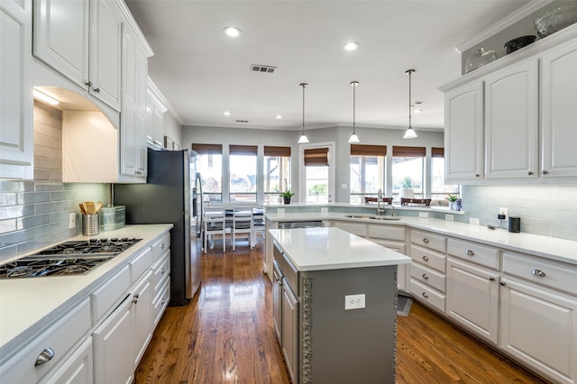 kitchen featuring appliances with stainless steel finishes, sink, a center island, white cabinetry, and hanging light fixtures