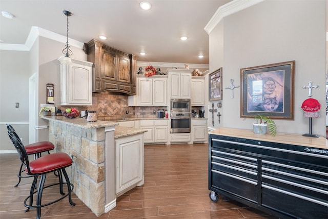 kitchen with light stone counters, decorative light fixtures, a breakfast bar area, decorative backsplash, and appliances with stainless steel finishes