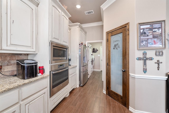 kitchen featuring appliances with stainless steel finishes, light stone counters, ornamental molding, separate washer and dryer, and white cabinets