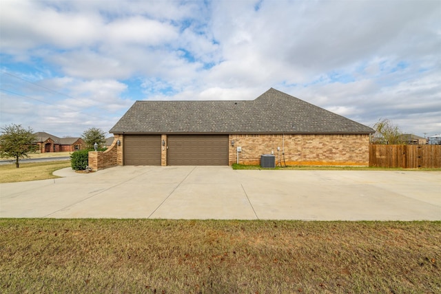 view of side of property with a yard, central AC, and a garage