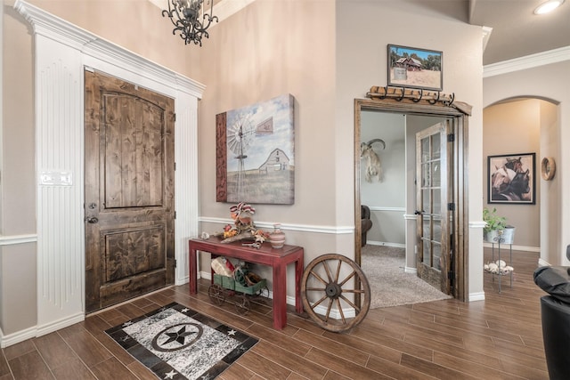 entryway with an inviting chandelier and crown molding