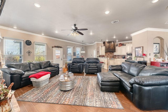 living room featuring light hardwood / wood-style floors, ceiling fan, and ornamental molding