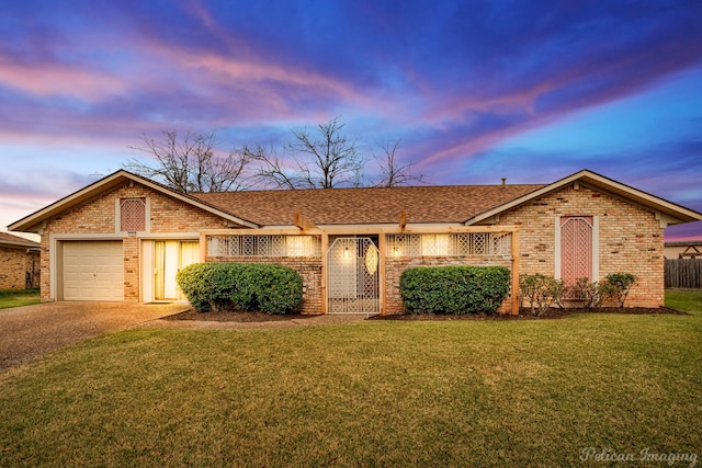 single story home featuring a lawn and a garage