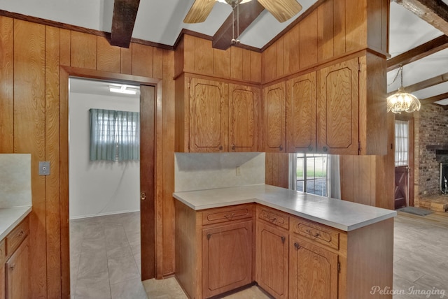 kitchen with ceiling fan, beam ceiling, wooden walls, decorative light fixtures, and kitchen peninsula