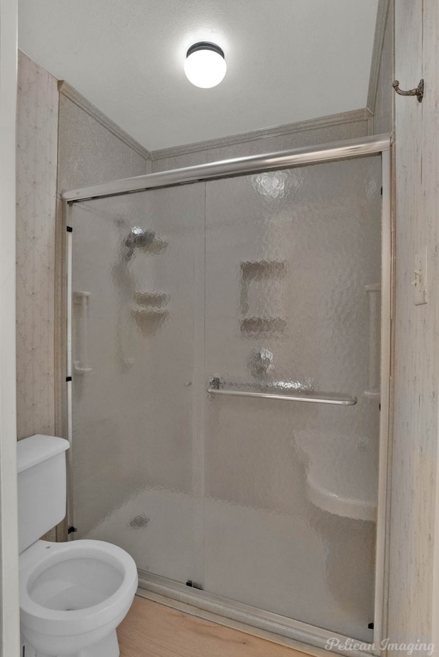 bathroom featuring hardwood / wood-style floors, a shower with shower door, and toilet