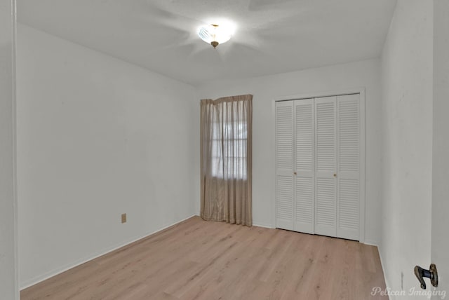 unfurnished bedroom with a closet and light wood-type flooring