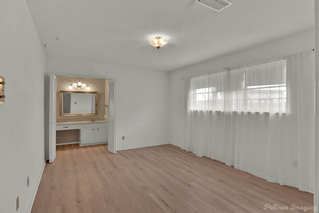 unfurnished bedroom featuring connected bathroom and light hardwood / wood-style floors