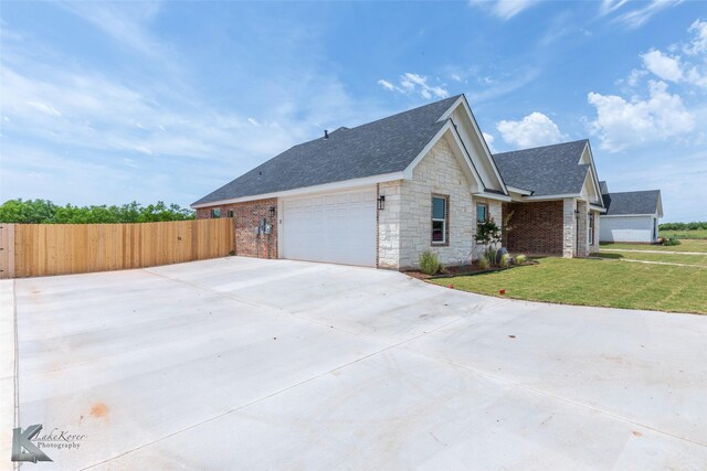 145 Colorado, Abilene, TX 79606 - view of side of home featuring roof with shingles, stone siding, driveway, and a garage