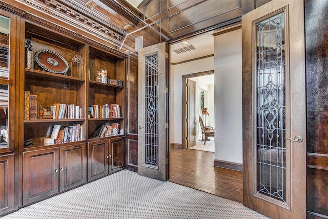 interior space with carpet flooring, built in features, and crown molding