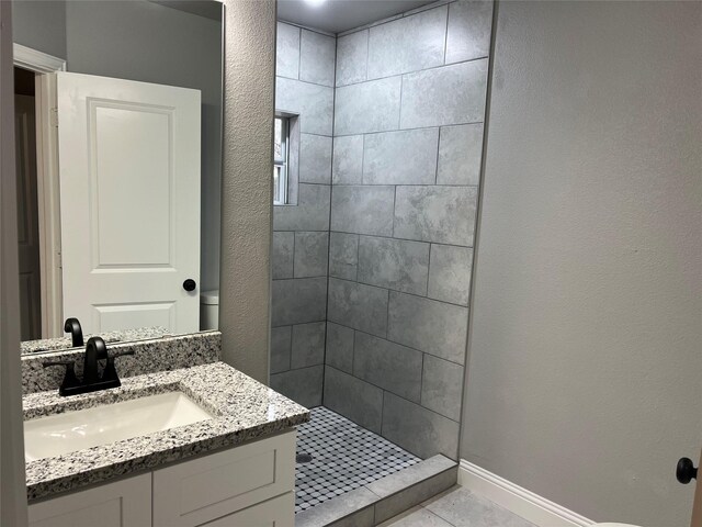 bathroom with a tile shower, tile patterned floors, vanity, and toilet