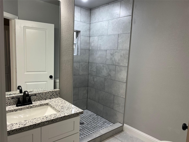 bathroom with tile patterned flooring, vanity, tiled shower, and toilet