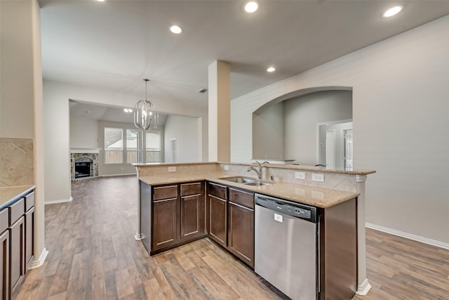 kitchen with sink, stainless steel dishwasher, a notable chandelier, decorative light fixtures, and a fireplace