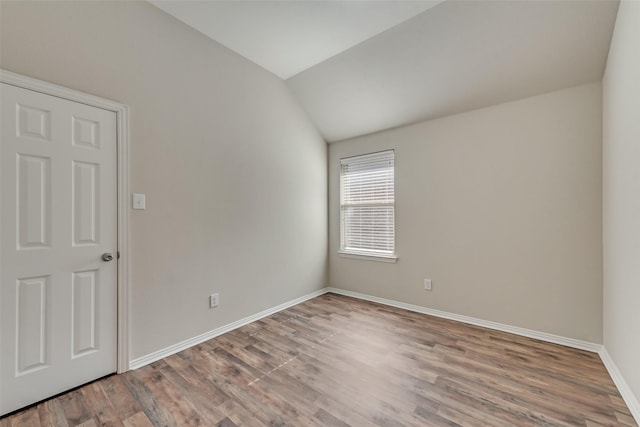 spare room featuring wood-type flooring and lofted ceiling