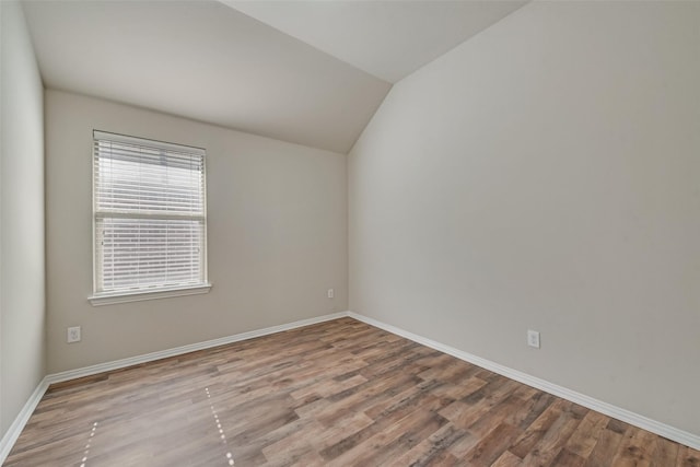 spare room featuring light wood-type flooring and lofted ceiling