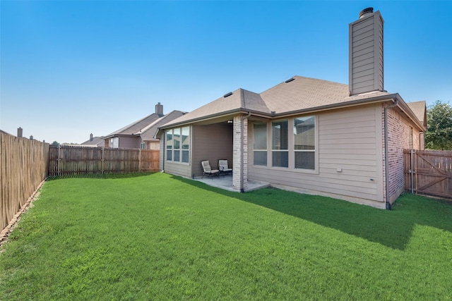 back of house with a lawn and a patio