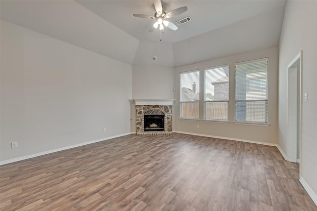 unfurnished living room featuring light wood-type flooring, a stone fireplace, ceiling fan, and lofted ceiling