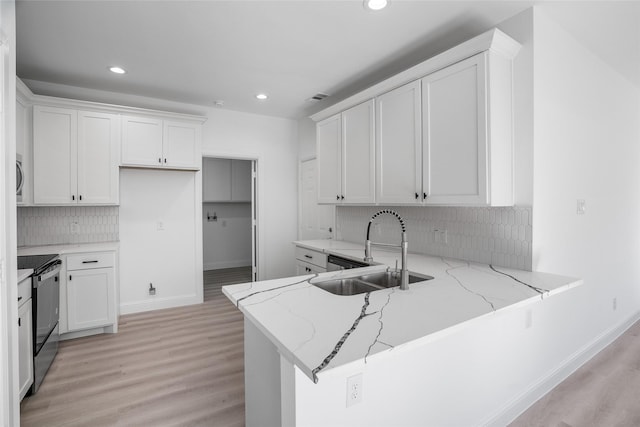 kitchen featuring kitchen peninsula, light stone countertops, black range with electric stovetop, sink, and white cabinetry