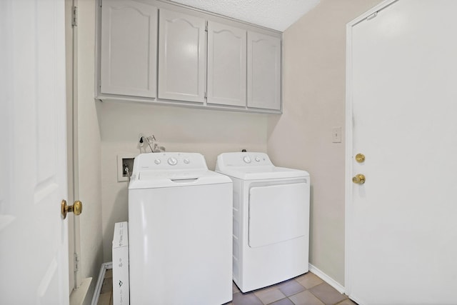 clothes washing area featuring tile patterned floors, washer and clothes dryer, cabinets, and a textured ceiling