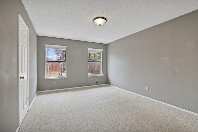 empty room with light colored carpet and a textured ceiling