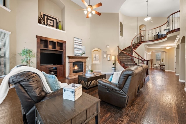 living room featuring dark hardwood / wood-style floors, built in shelves, a high ceiling, and ceiling fan