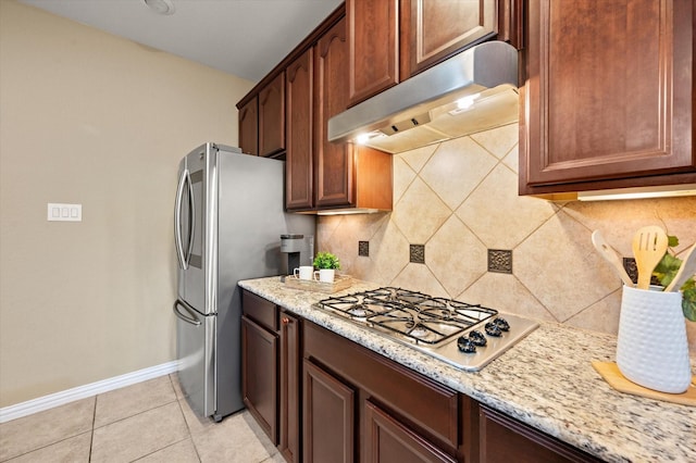 kitchen with light tile patterned floors, appliances with stainless steel finishes, decorative backsplash, and light stone counters