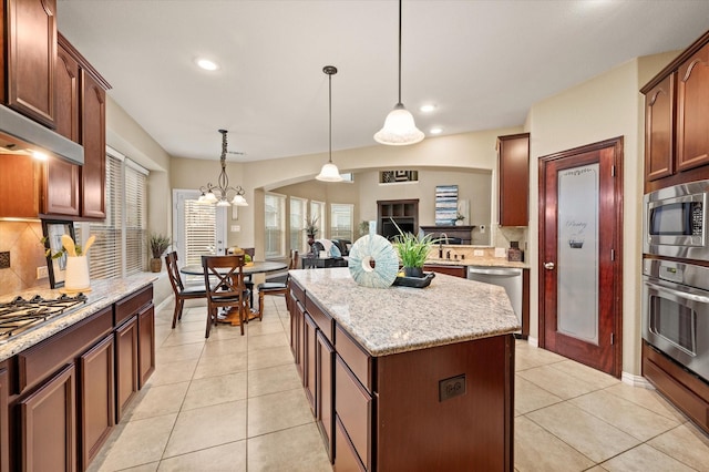 kitchen featuring tasteful backsplash, a center island, pendant lighting, light tile patterned flooring, and appliances with stainless steel finishes