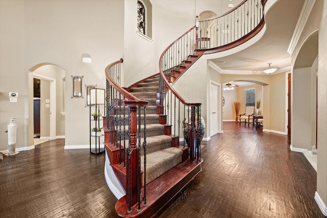 stairway featuring hardwood / wood-style floors, ornamental molding, and a towering ceiling