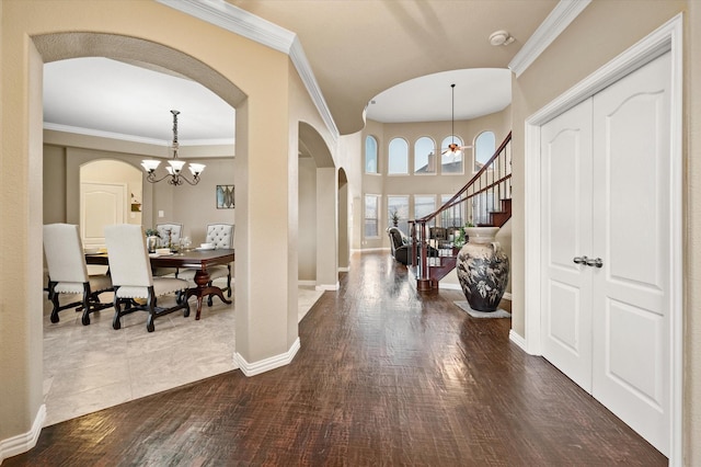 foyer featuring dark wood-type flooring, crown molding, and a notable chandelier