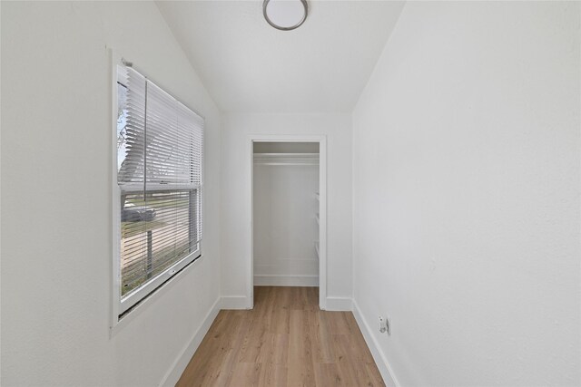 hallway with lofted ceiling and light wood-type flooring