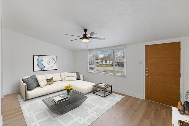 living room with ceiling fan, light wood-type flooring, and a textured ceiling