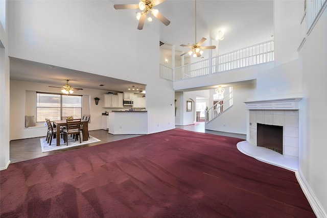 living room with ceiling fan, a fireplace, and a high ceiling